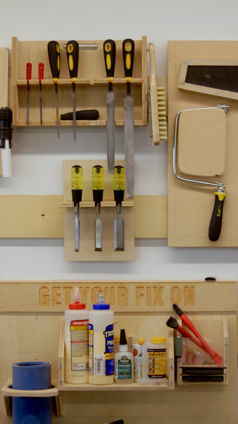 Woodworking tools and glue bottles neatly arranged on workshop wall.