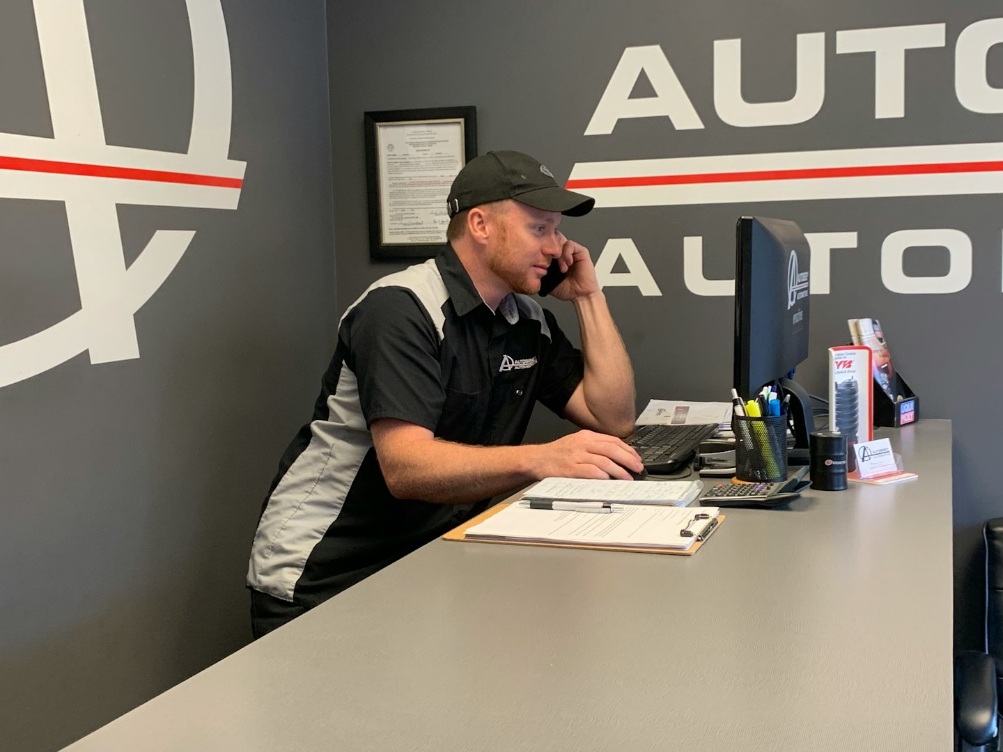 Service worker talks on the phone at a computer desk.