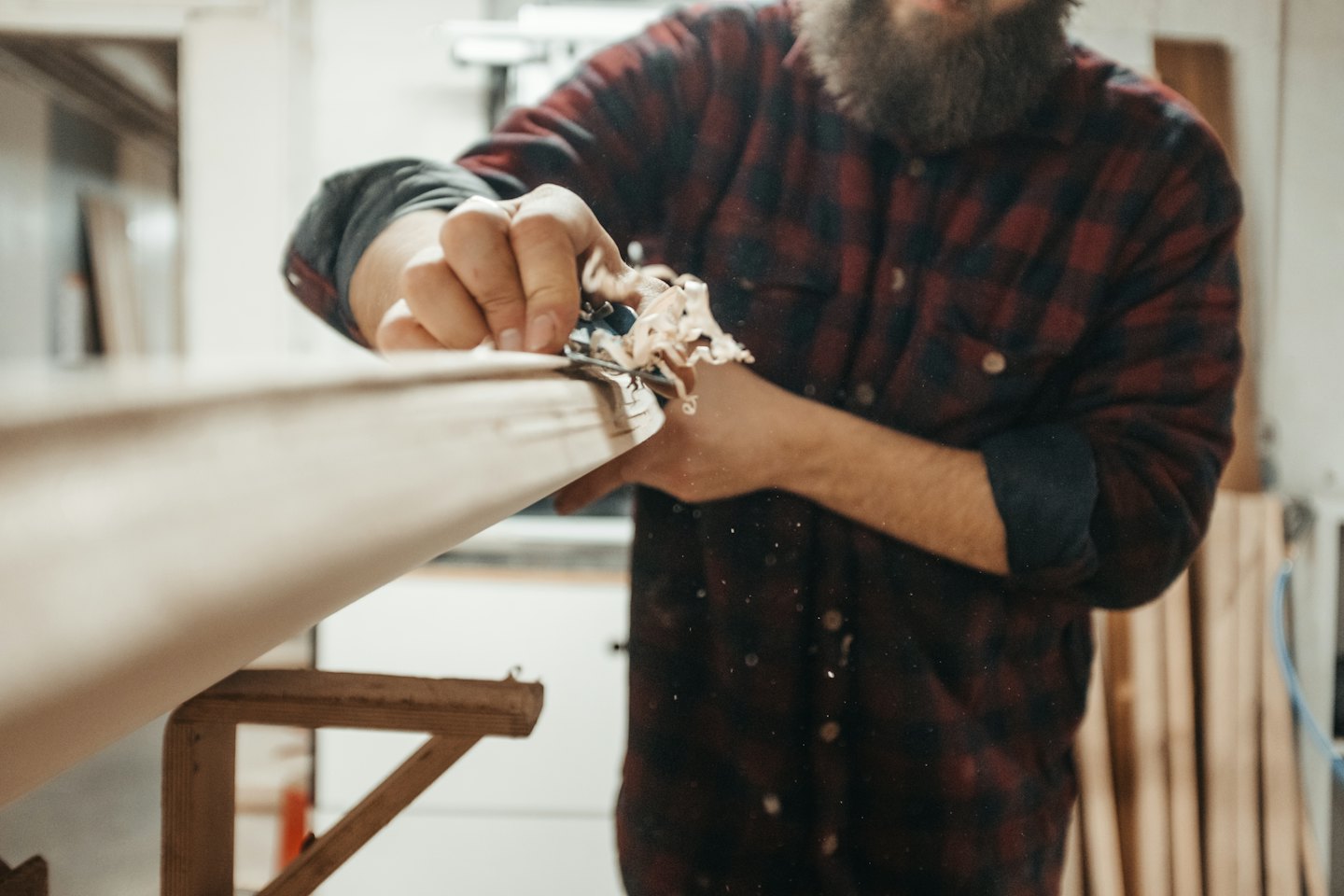 Carpenter uses a hand plane to shape a wooden board.