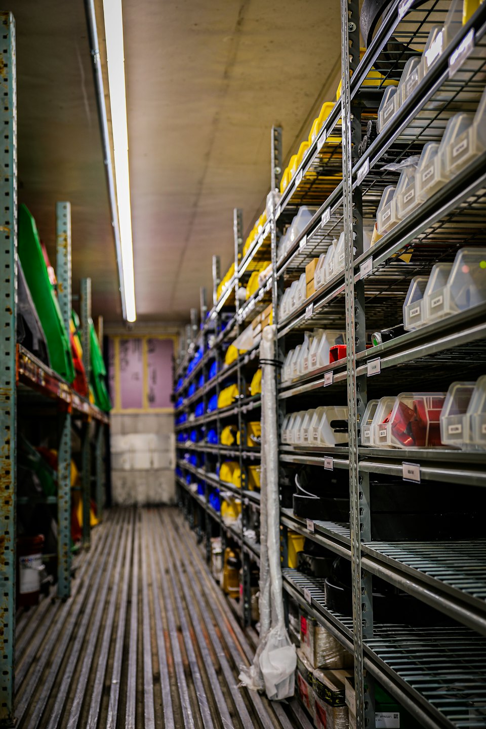Warehouse aisle between tall shelves stocked with parts.