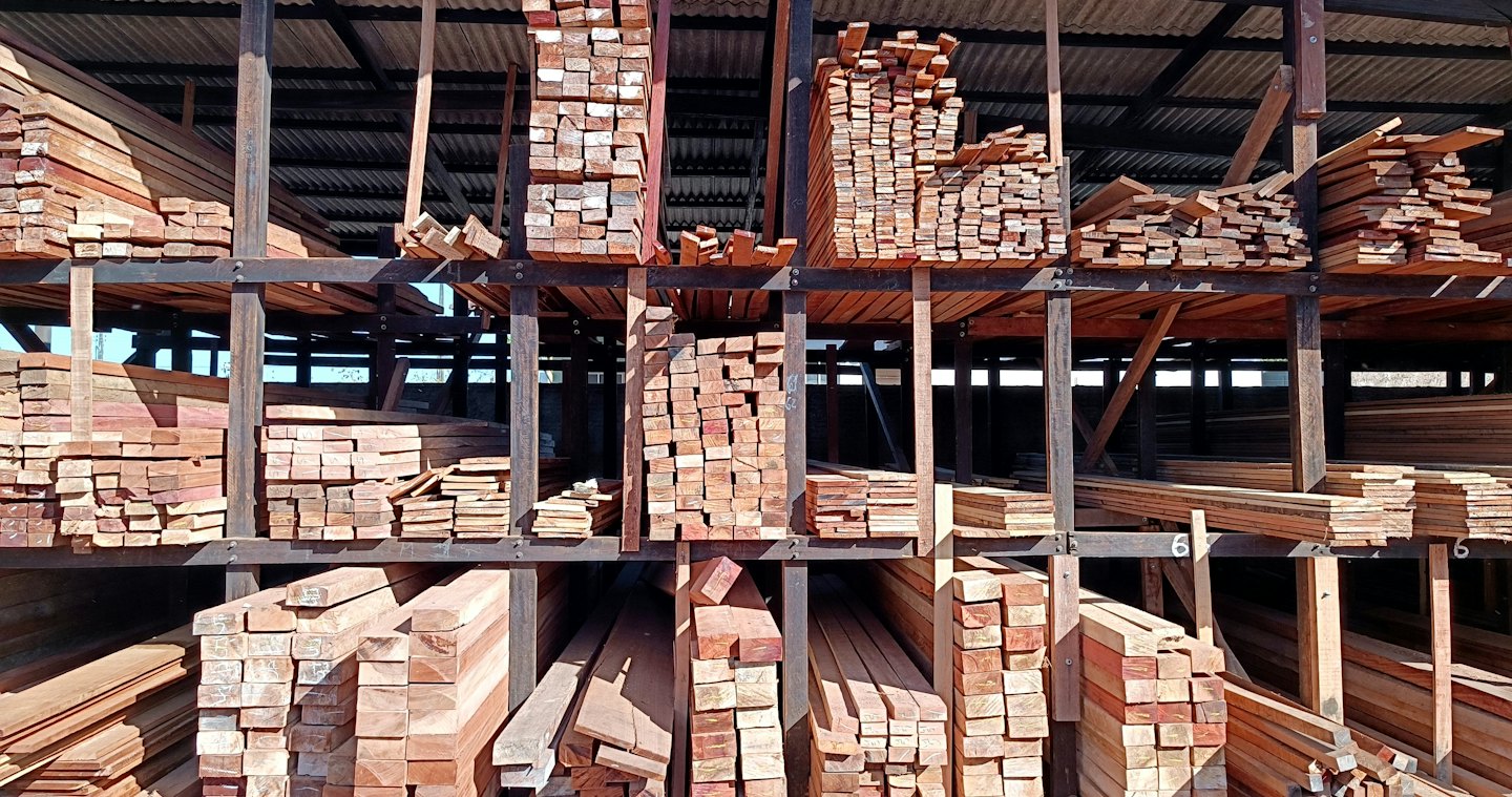 Stacked timber planks fill the shelves of an organized lumberyard.